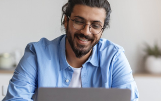 Man with glasses using a computer sitting next to the drink coach logo