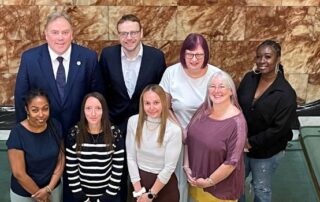 Jason Perry, Kristian Aspinall and the Expert by Experience Panel standing in the Town Hall