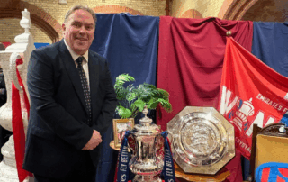 Mayor Perry standing next to the FA Cup and a shield in front of a Crystal Palace flag.