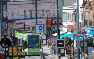 People walking in Croydon town centre with a tram in the distance.