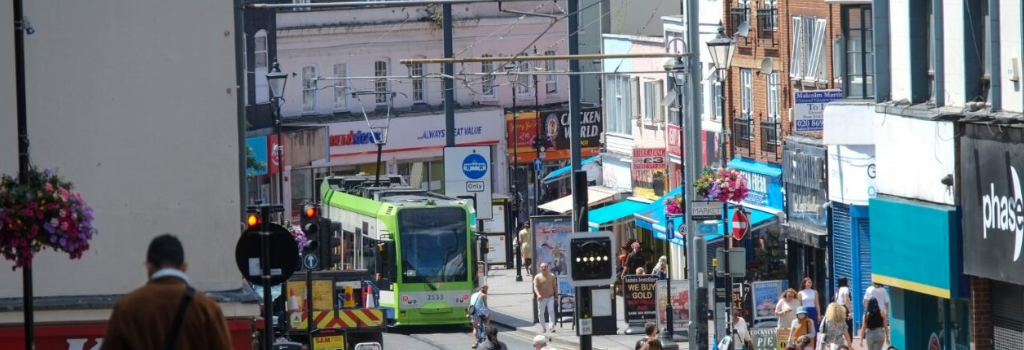 People walking in Croydon town centre with a tram in the distance.