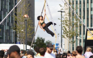 Circus performer balances above a crowd of spectators.