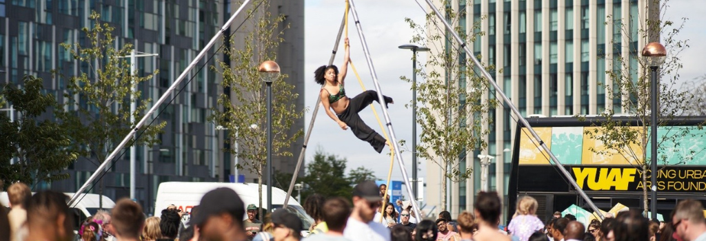 Circus performer balances above a crowd of spectators.