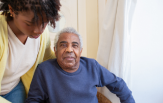 Man sitting down and being helped by a carer.