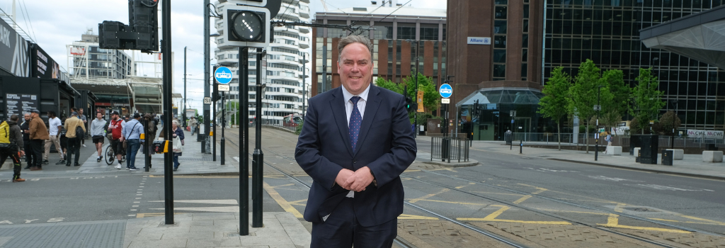 Mayor Perry stands in Croydon town centre with the 50p building behind him.